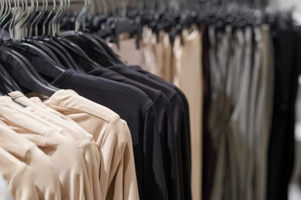 Close-up of sustainable clothing in neutral tones hanging on black hangers in a retail store