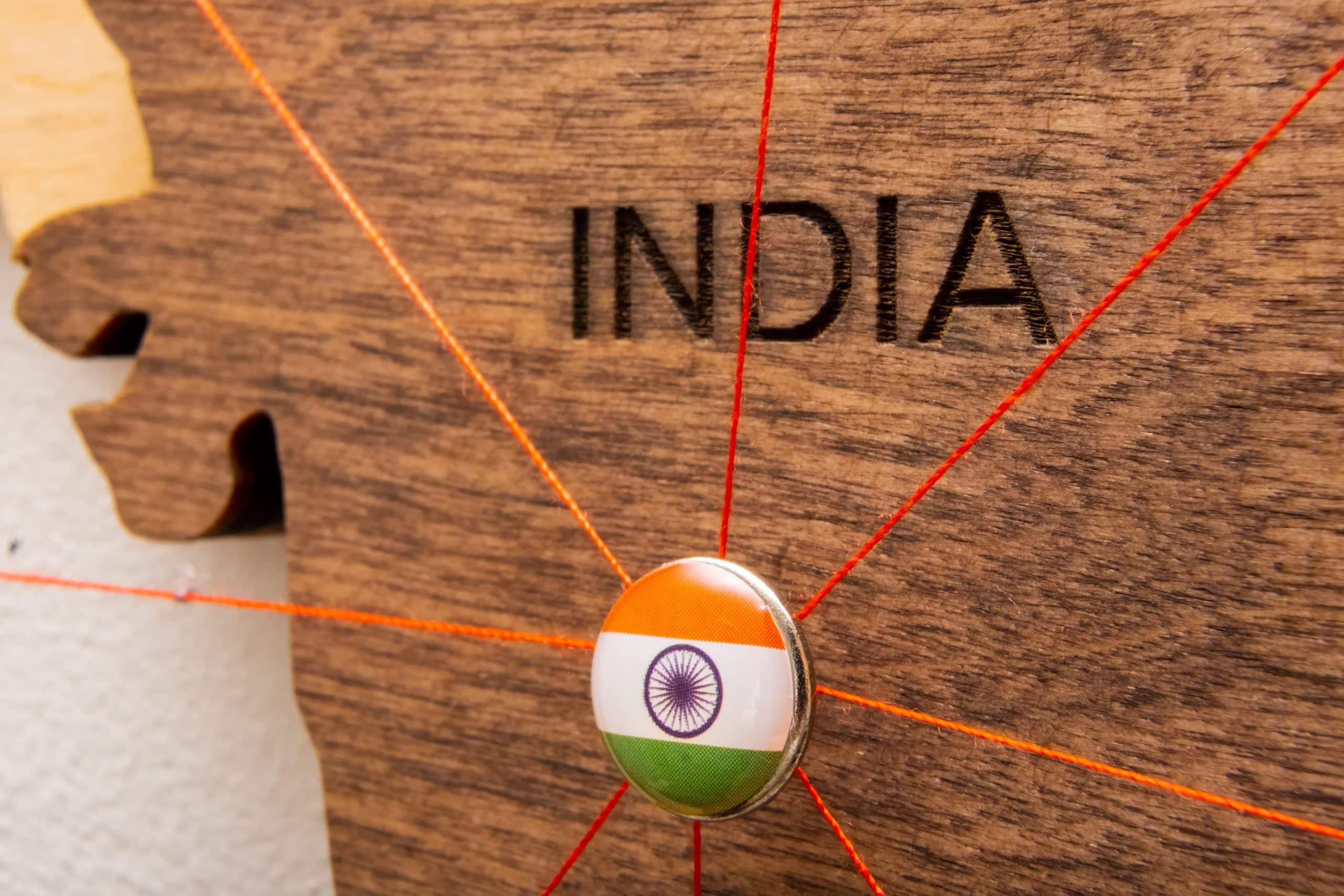 India flag pins connected by red thread, symbolizing global trade, import-export routes, and India's growing textile footprint.